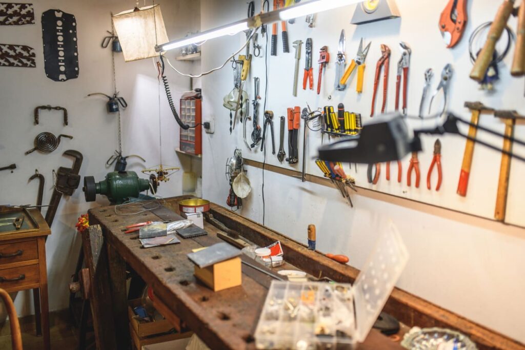 A busy workshop with a wooden workbench, tools on a pegboard, and bright overhead lighting highlighting the space's organized disorder.