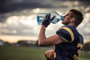football player staying hydrated during practice in hot temperatures