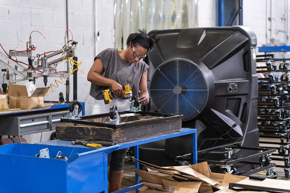 Woman installs hardware on durable castors for a brand new unit under construction.