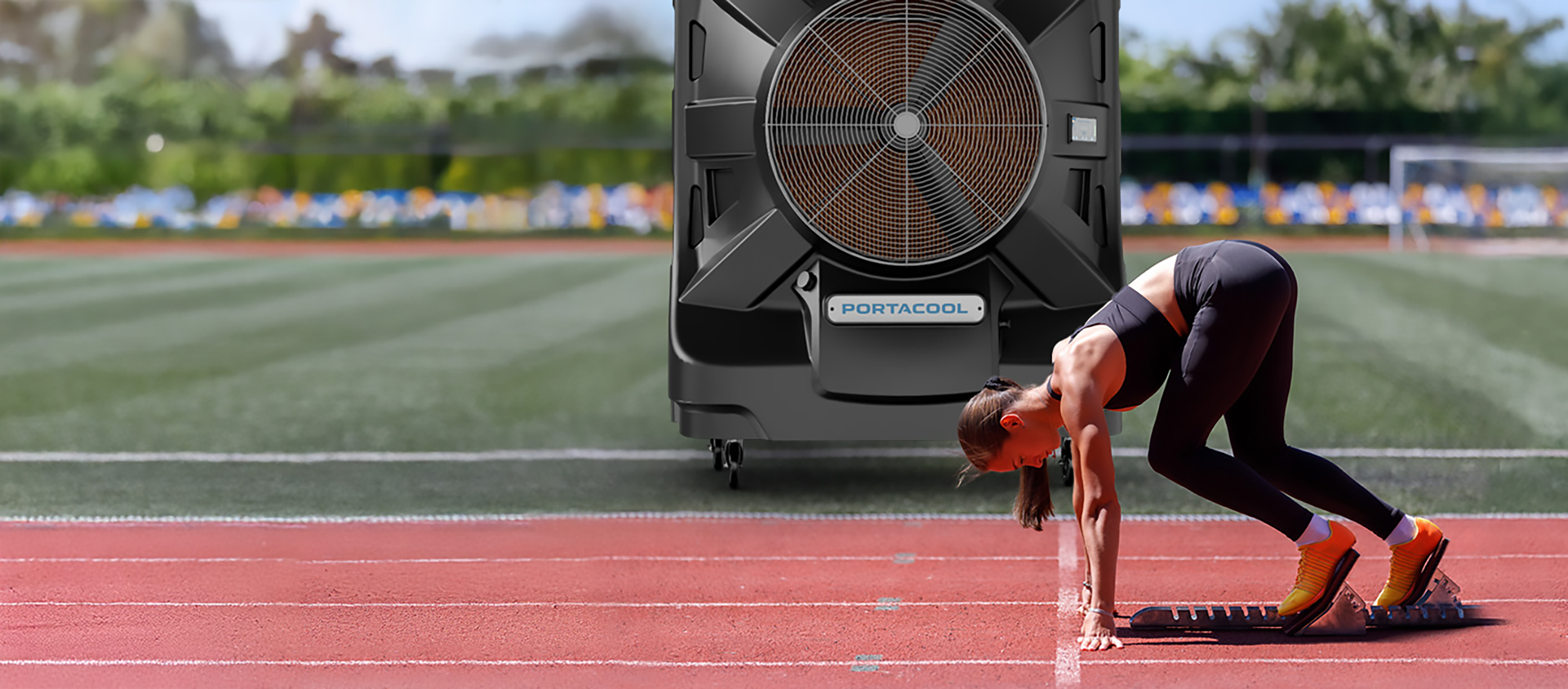 Female athlete at track start line; Portacool unit nearby, lush greenery in the background.