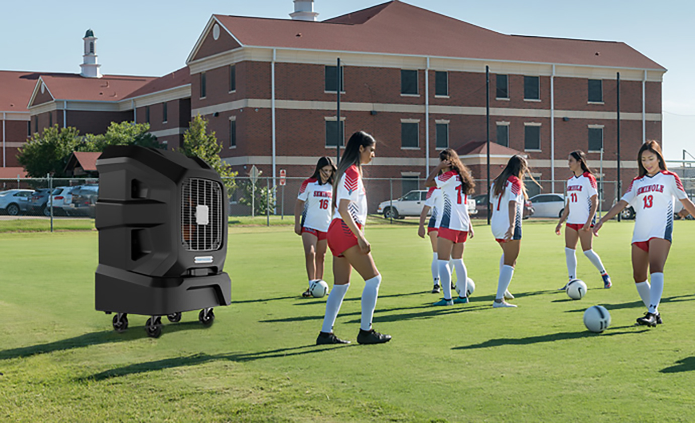 Girls practice soccer with a portable air cooler on the field, providing cooling relief and allowing for top performance.