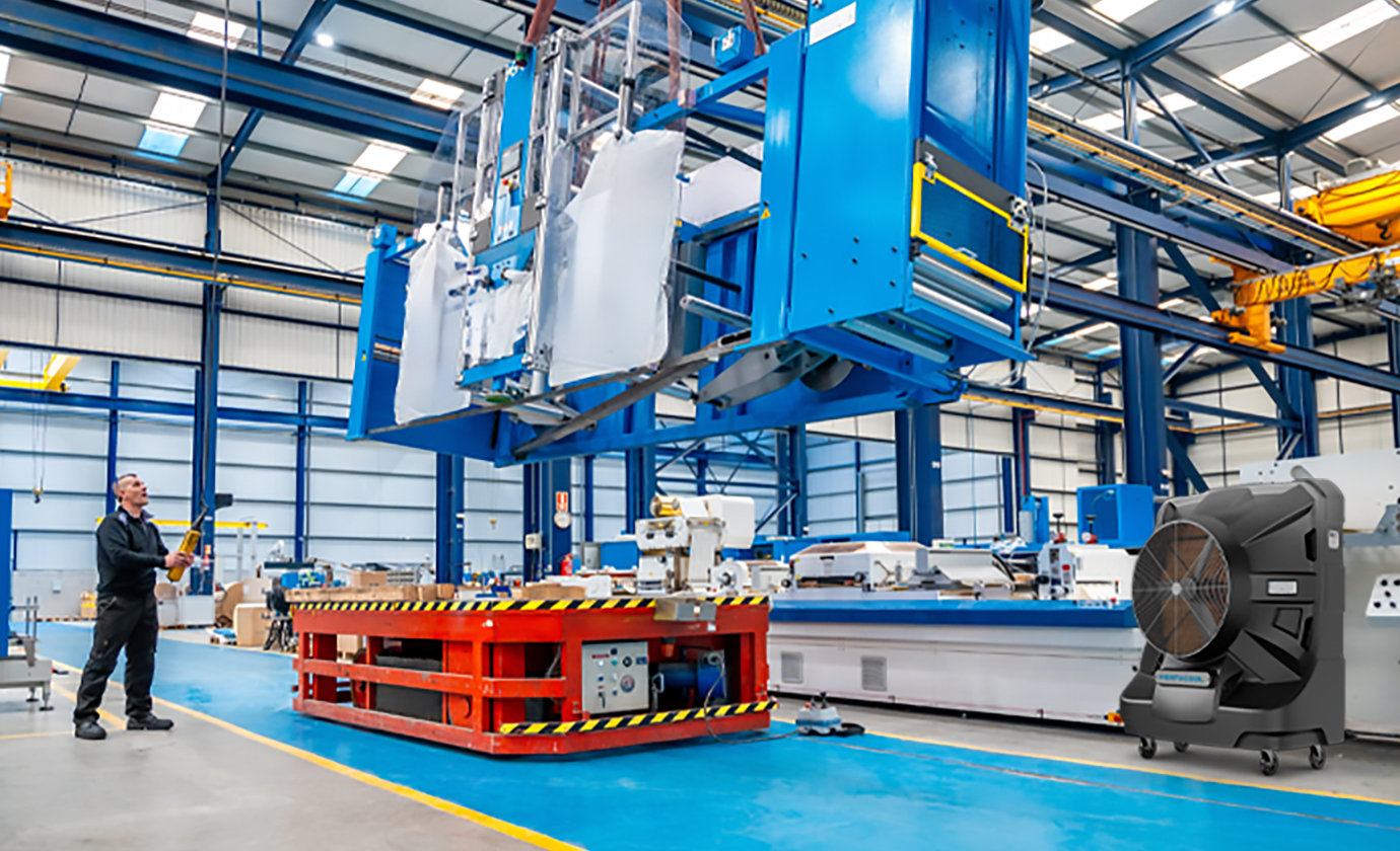 A worker operates a large blue machine in a warehouse with metal beams and industrial equipment.